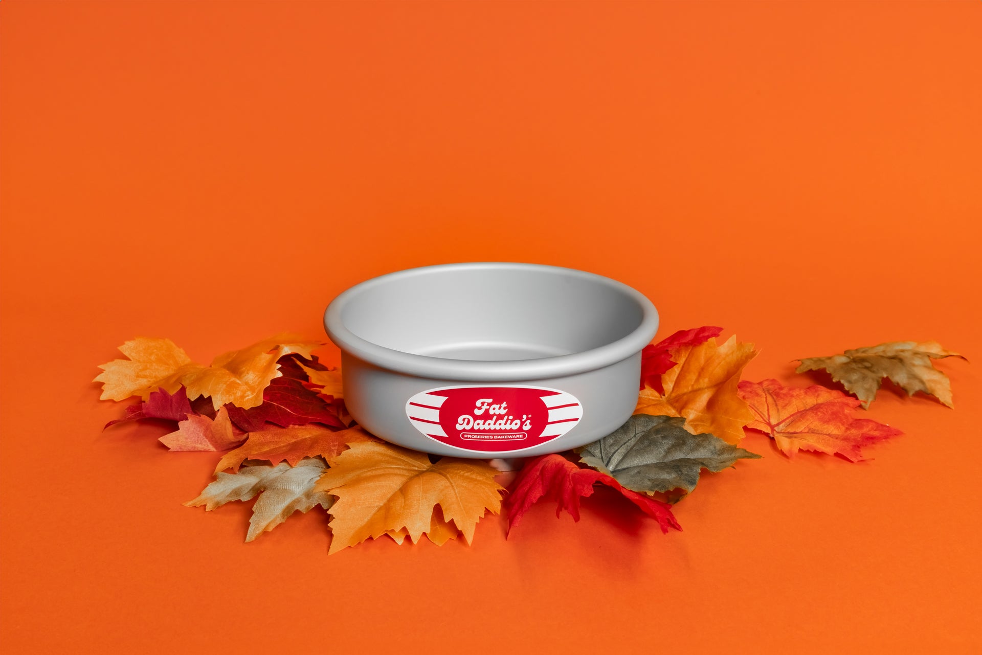 A round cake pan sitting on fall leaves on an orange background