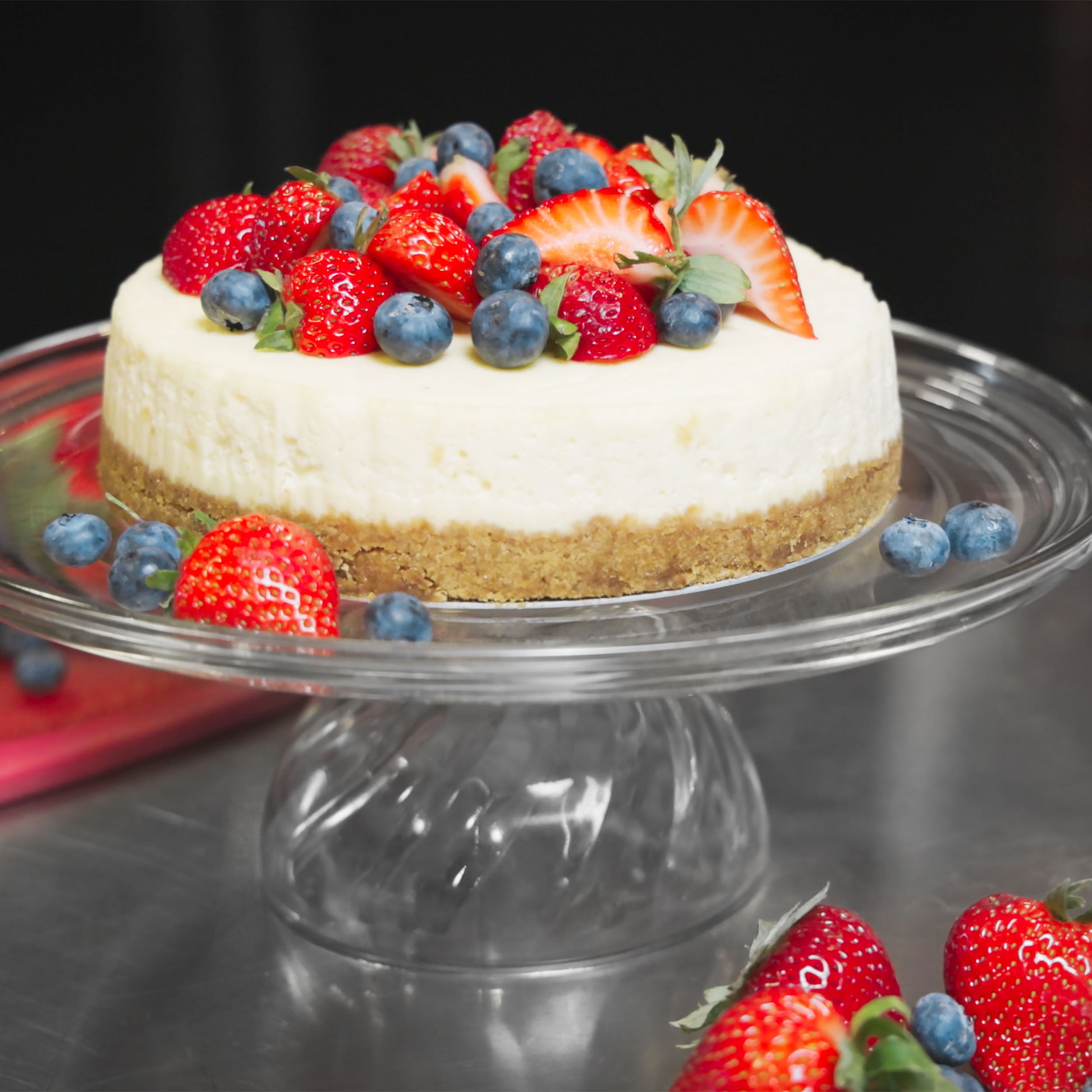 New York Cheesecake with strawberries and blueberries on a cake stand in a bakery