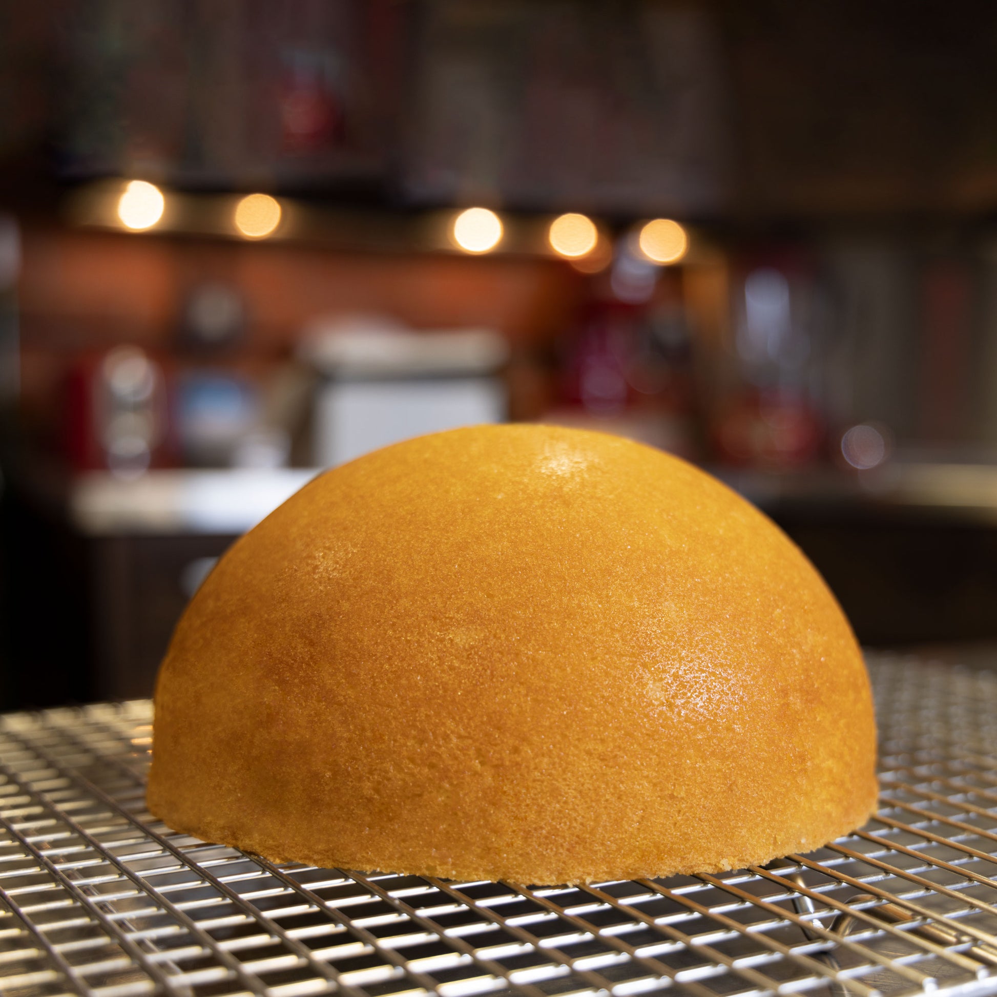 Hemisphere cake on a cooling rack in a commercial kitchen