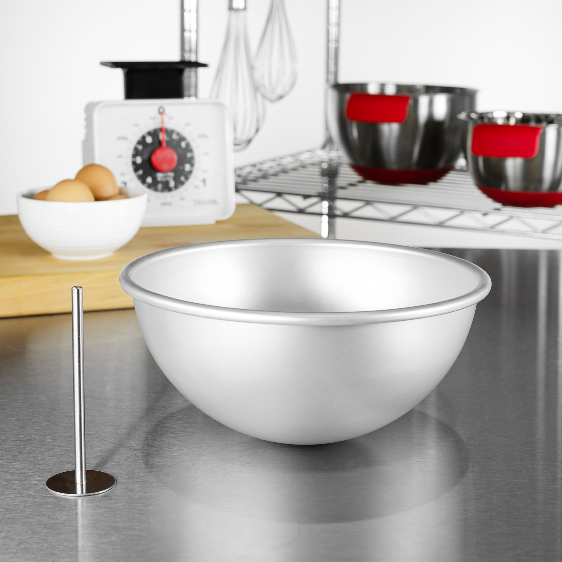 Hemisphere cake pan and heating core rod with eggs, kitchen scale, tools and bowls in a bakery