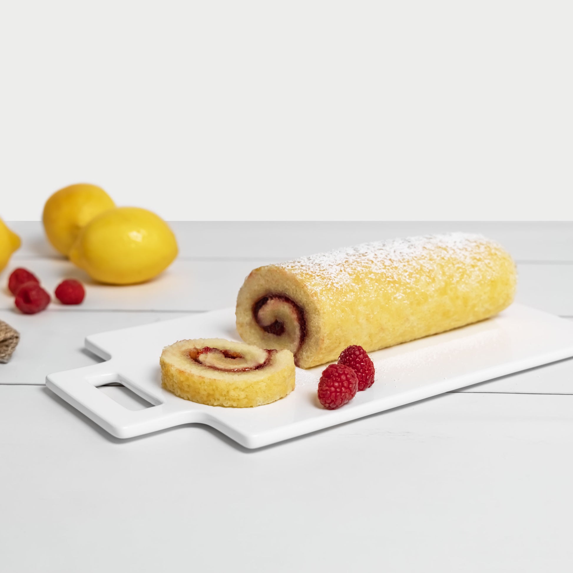 Yellow cake Jelly Roll with raspberries and lemons in a home kitchen