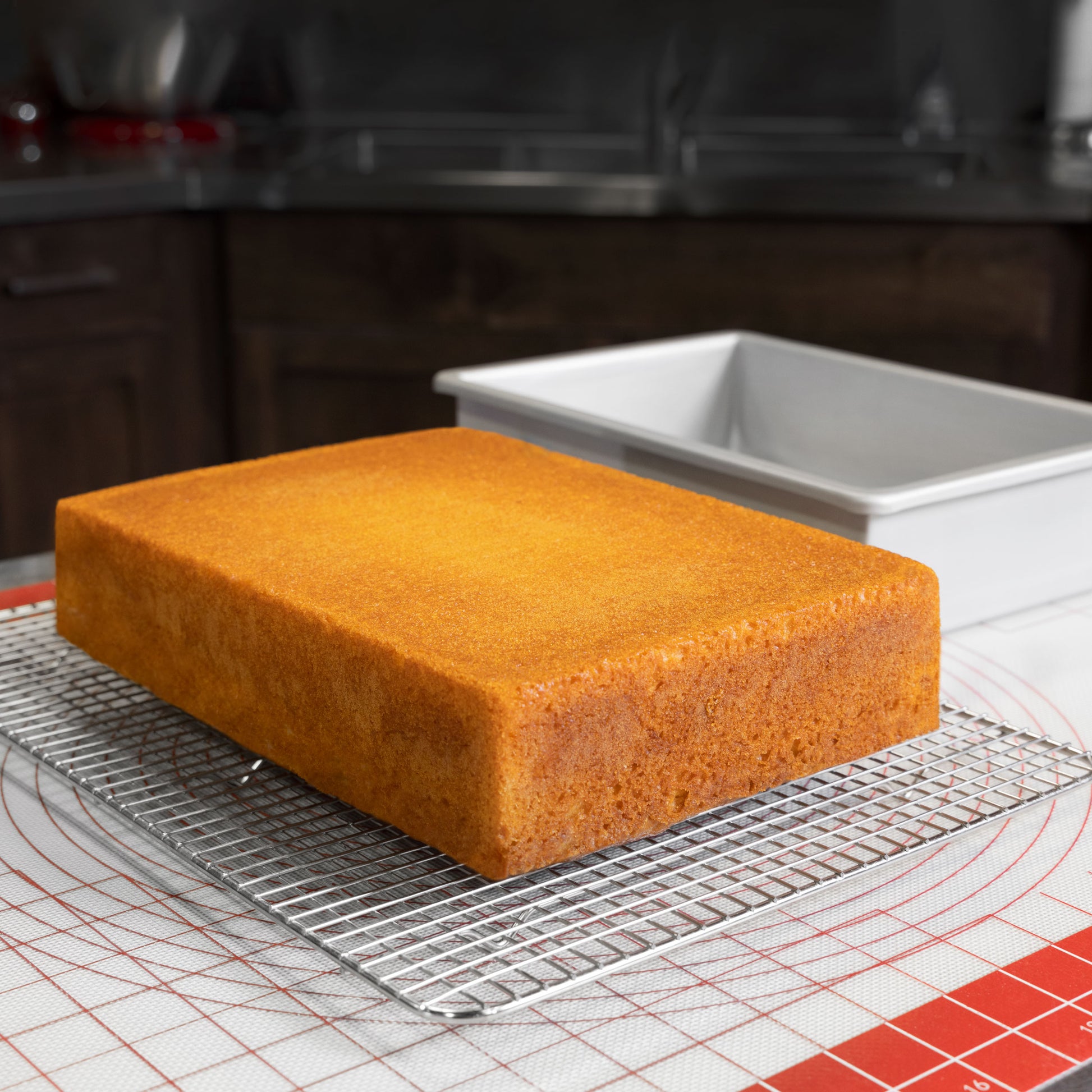 Rectangle sheet cake pan naked cake on cooling rack and work mat in a bakery