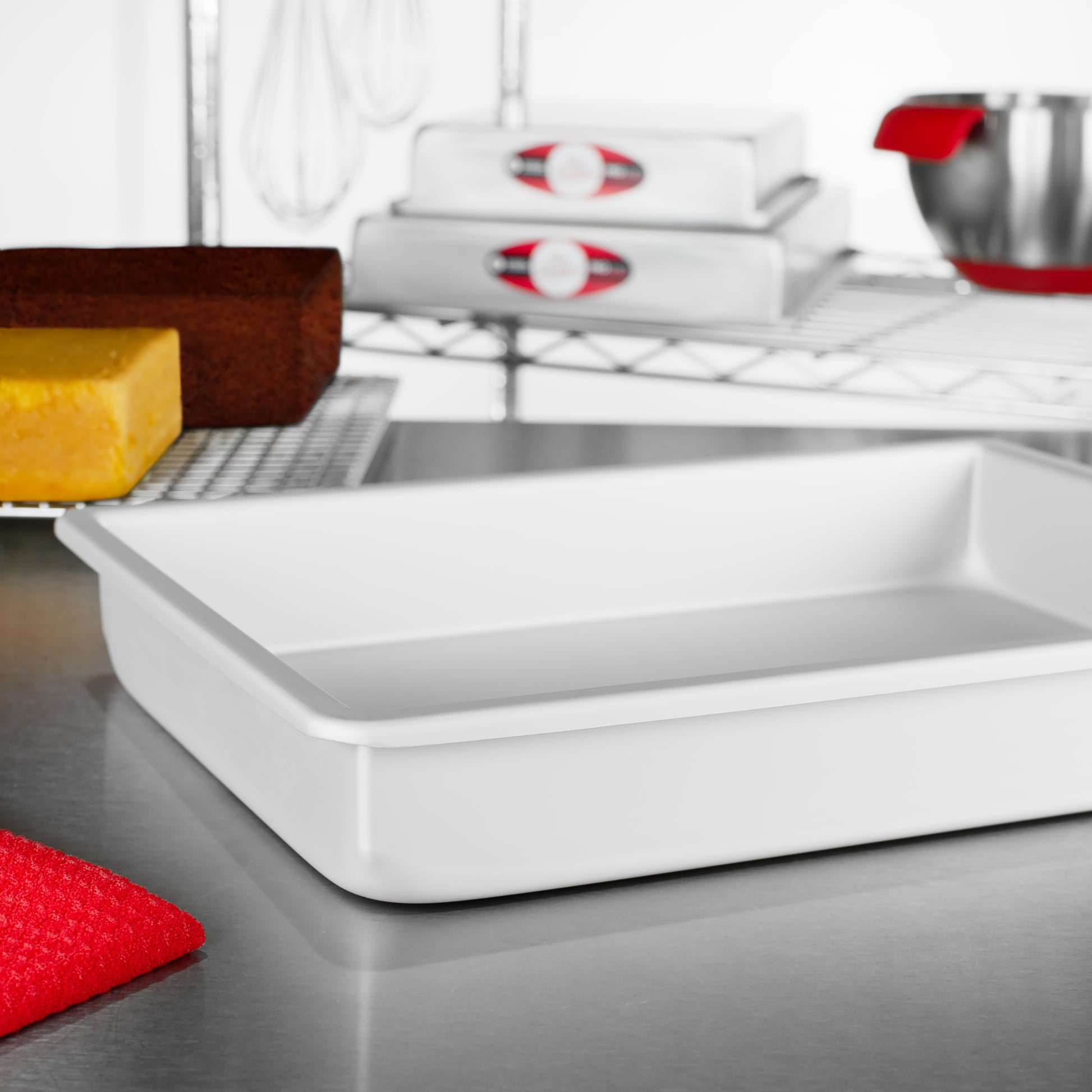 Rectangle sheet cake pans with sheet cakes, tools and bowls in a bakery