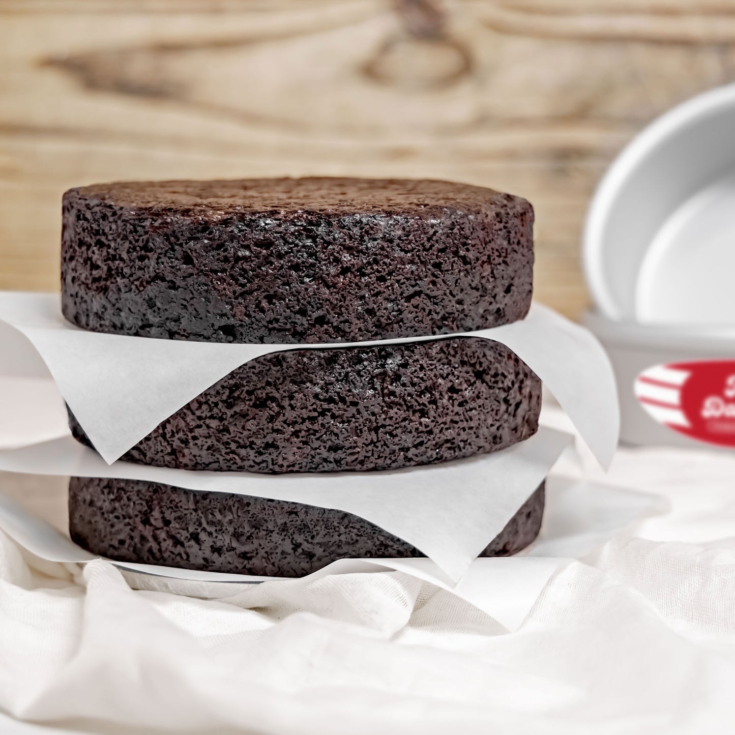 Three chocolate round cakes with pans in a home kitchen