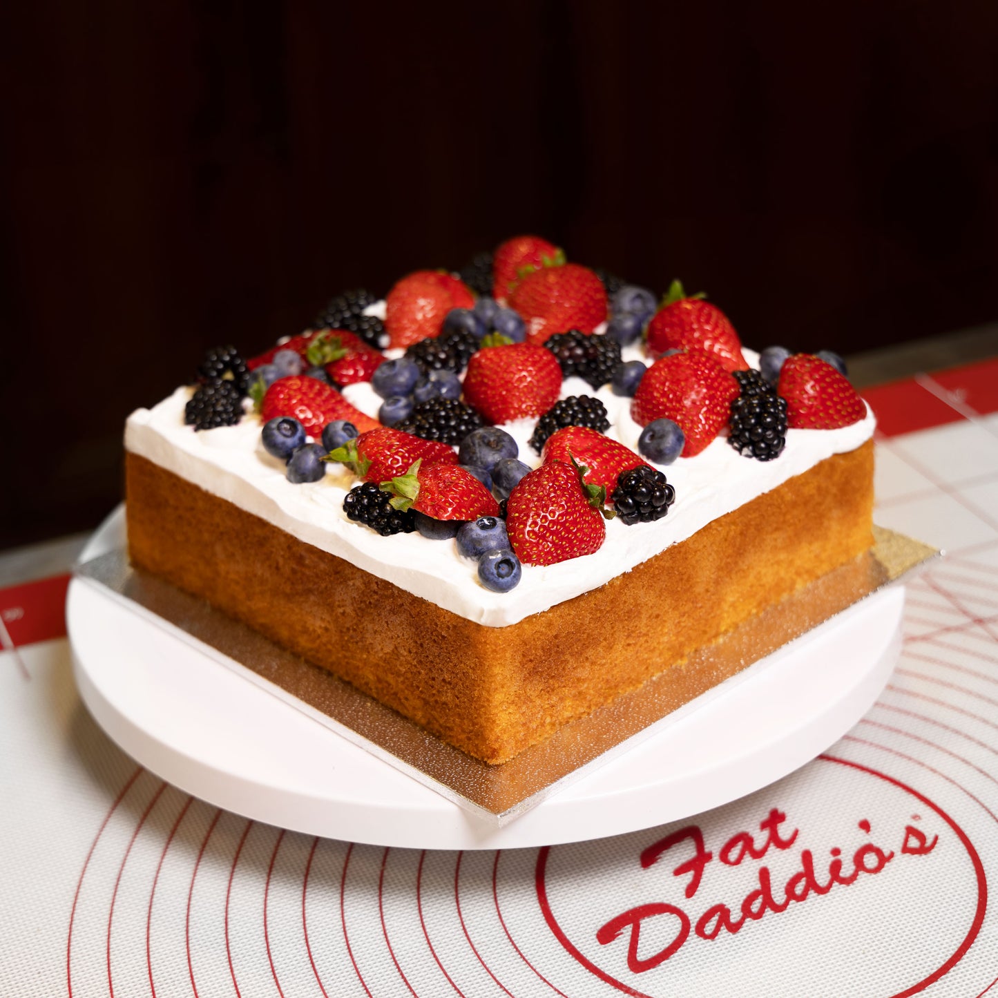 Fruit square naked cake pan on a turntable on a silicone baking mat in a commercial kitchen