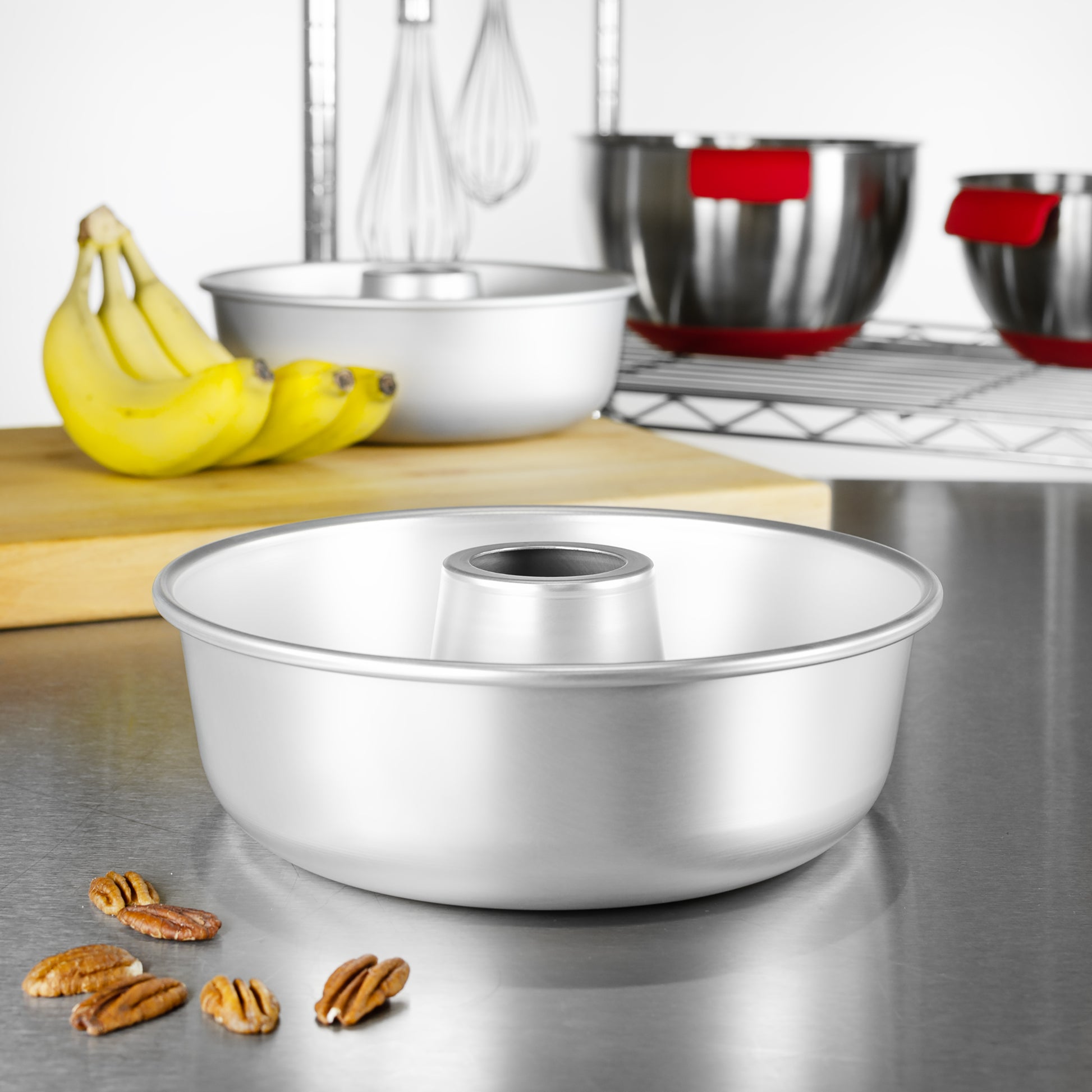 A ring mold pan with walnuts, bananas, tools and bowls in a bakery