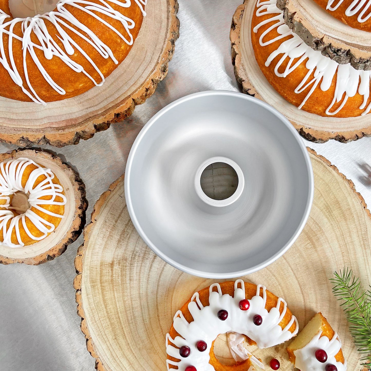 A ring mold pan surrounded by Christmas themed ring mold cakes with drizzled icing on wood rounds