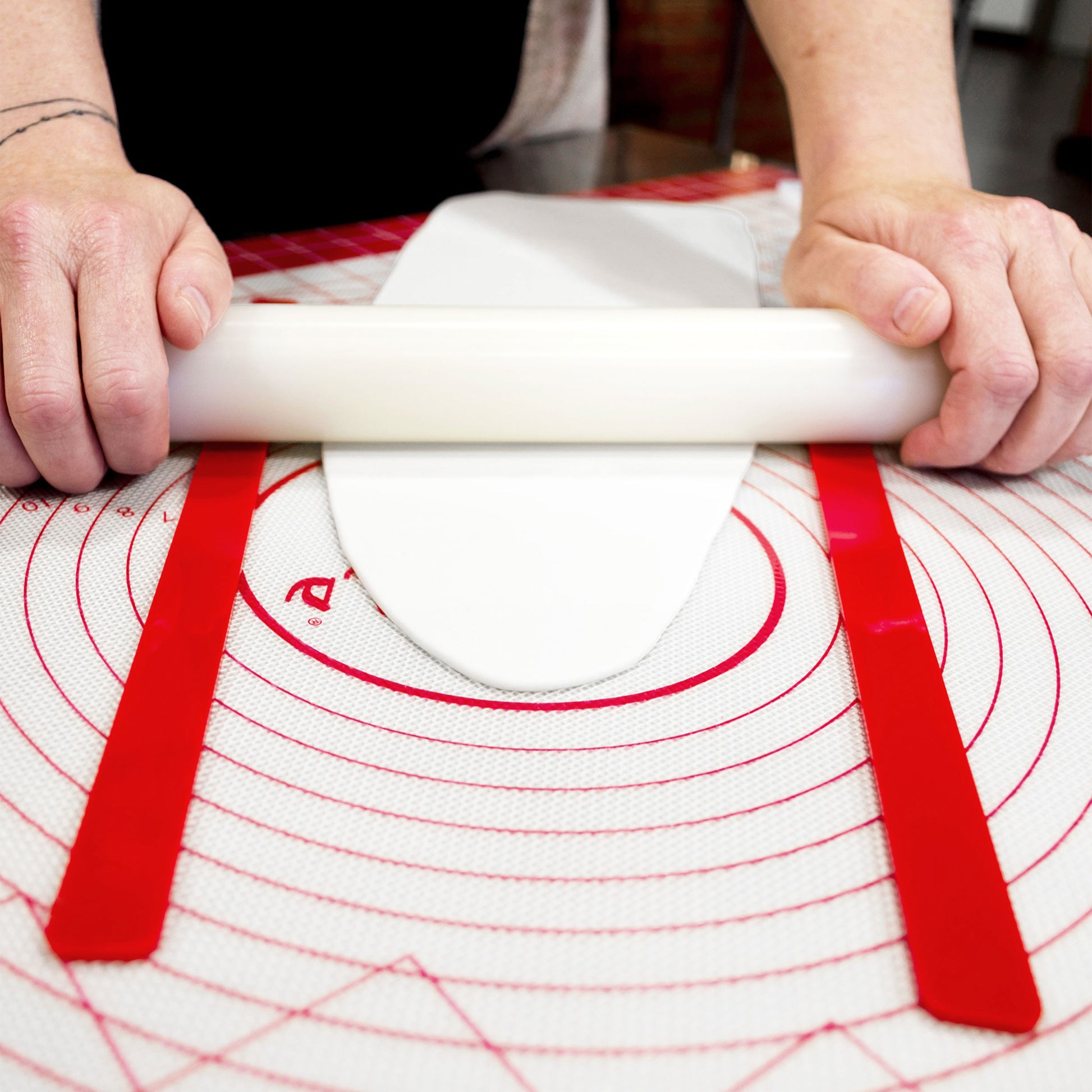 Silicone Work Mat and Dough Leveling Set used to measure height of white fondant by a baker