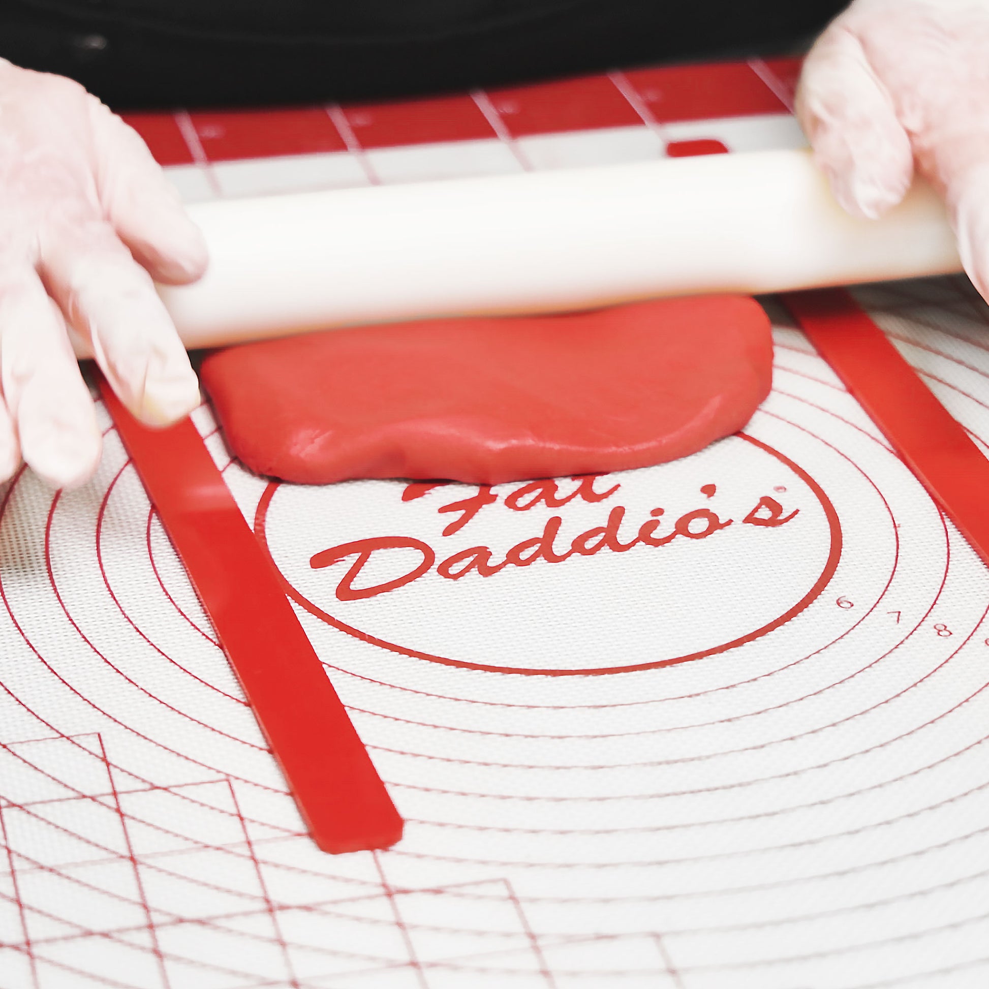 Silicone Work Mat and Dough Leveling Set used to measure height of red fondant by a baker