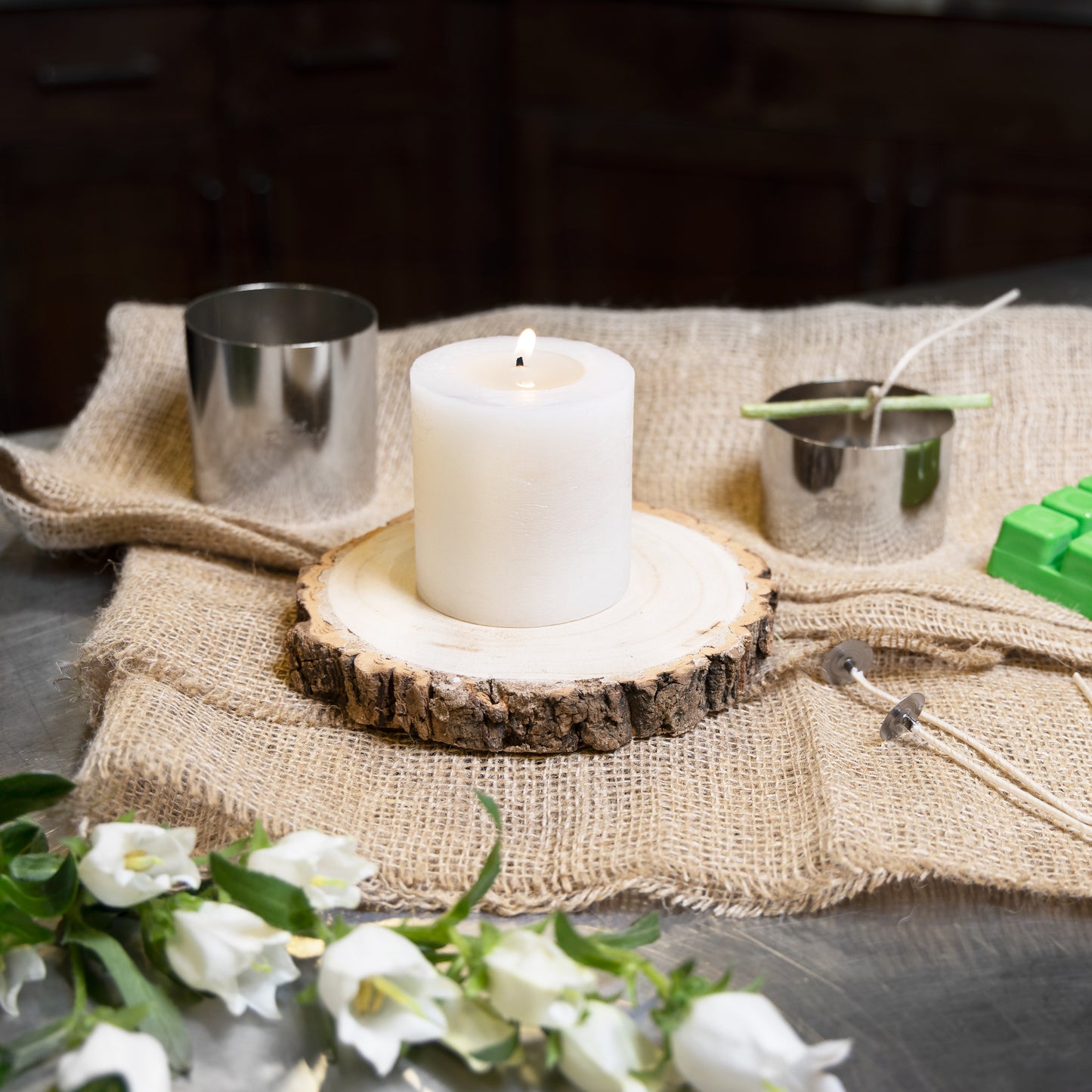 Cake and pastry ring used for candling making and crafting with a candle, wax, wicks and white flowers on burlap